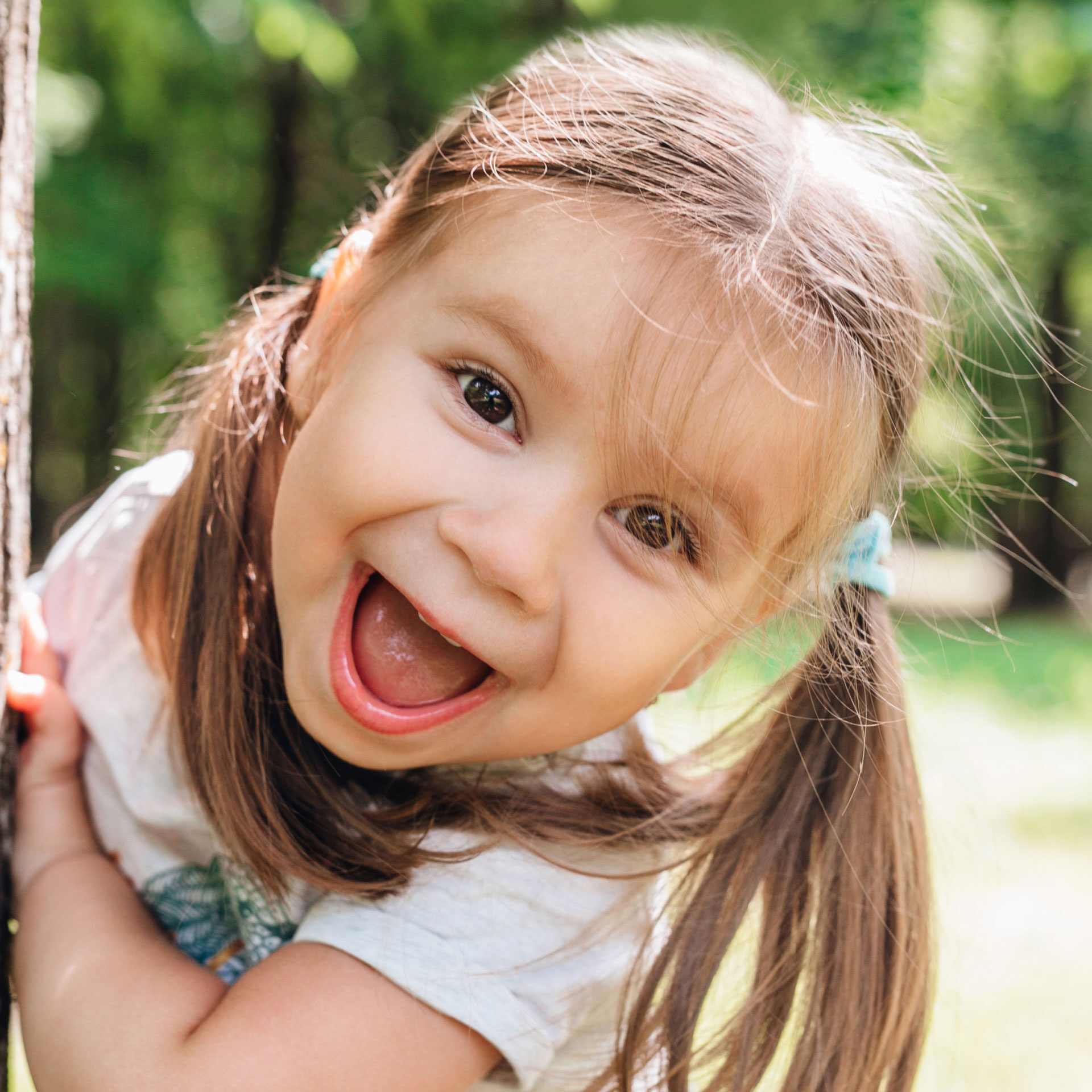 young girl with pigtails smiling at the camera while playing in the park